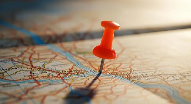 Orange pushpin marking a location on a detailed paper map