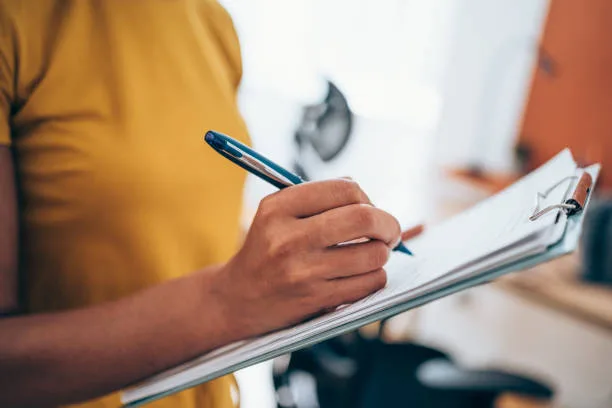 Person writing notes on a clipboard while evaluating a web design proposal